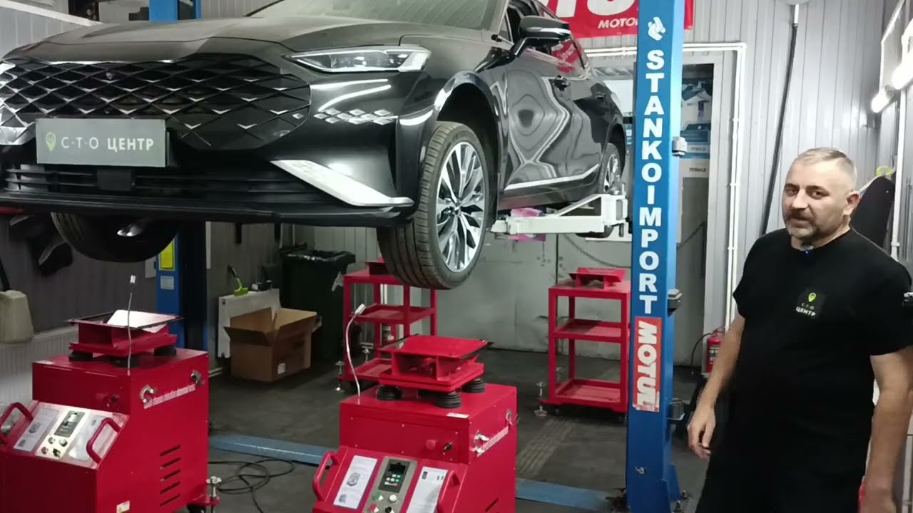 механик осматривает подвеску автомобиля на подъемнике